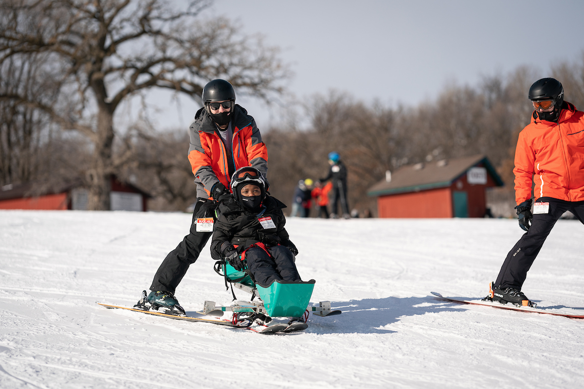 Volunteers help a skier go safely down the hill. 
