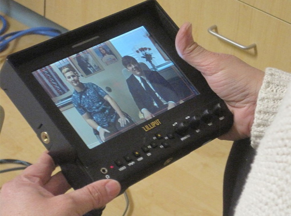 A teacher holds a broadcasting monitor. 