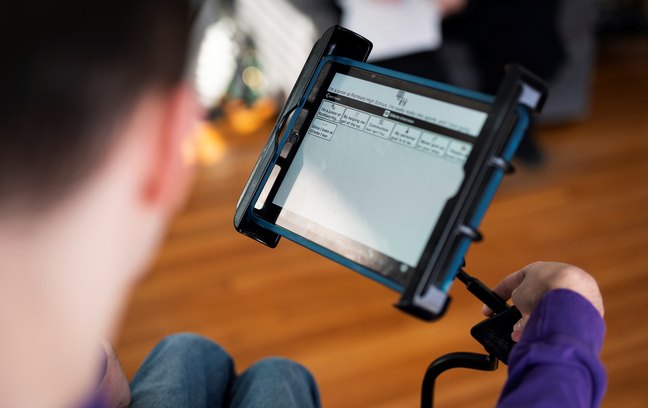 A child uses his AAC device, an iPad.