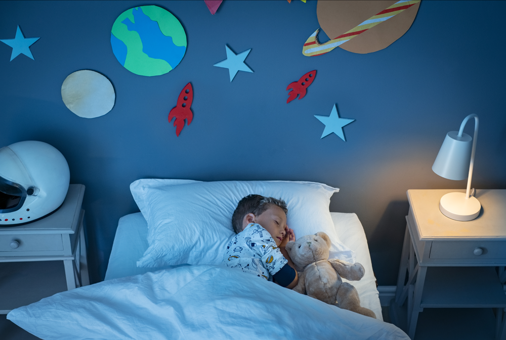A child sleeps in a space-themed decorated room. 