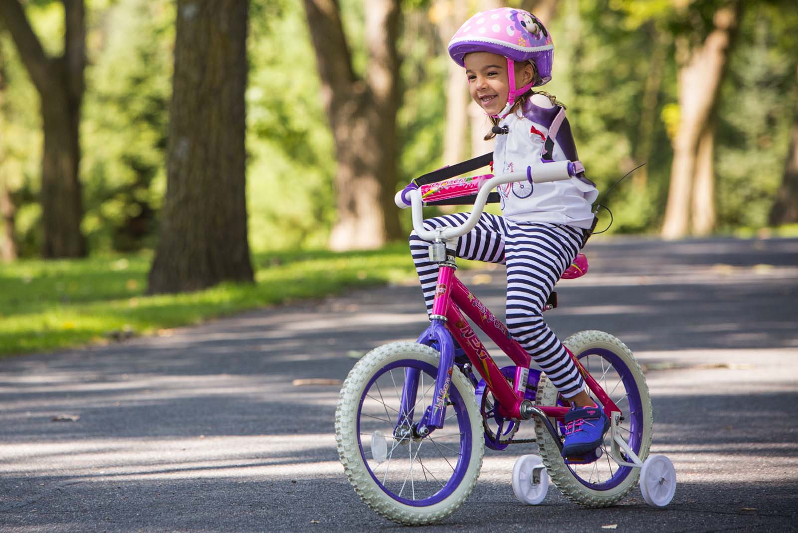 Gillette patient Ruth Evelyn (RE) who was born without arms rides her bike