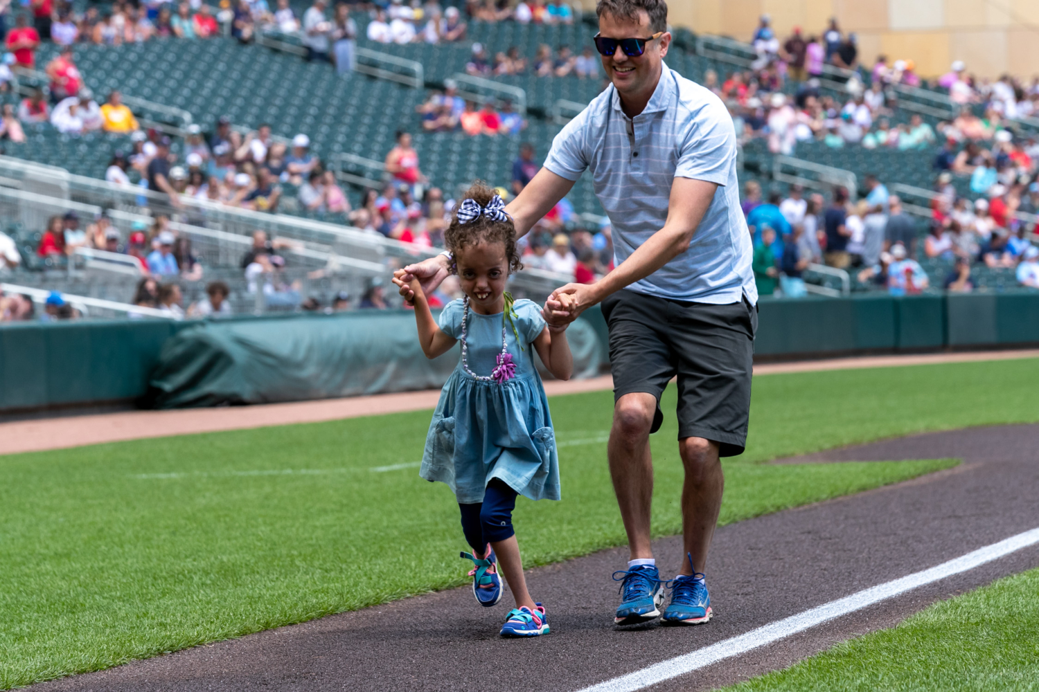 Peyton and her father run towards home plate at Target field