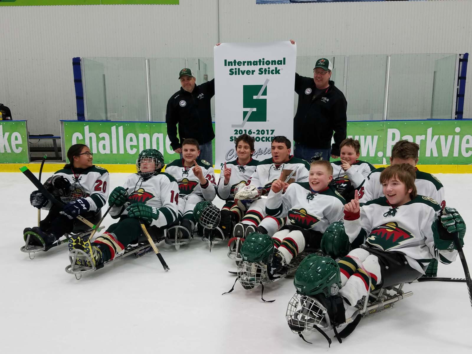 Joe and his hockey team on the ice holding a banner