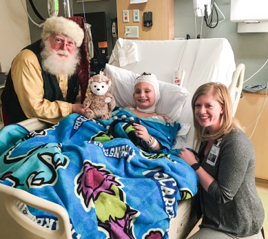 Santa Carlucci and Jamie Yuen bring some holiday cheer to Anthony as he recovers in the Gillette Pediatric Intensive Care Unit.