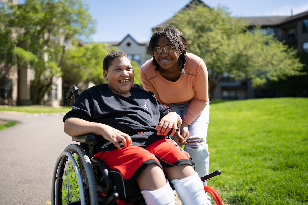 Gillette Children's patient Michael-Holley on a sunny day with his family member
