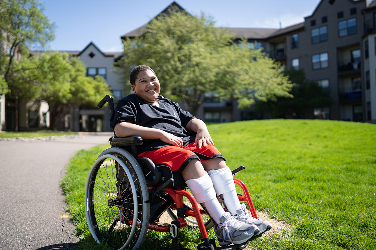 Gillette Children's patient, Michael Holley, sitting in a wheelchair in the yard.