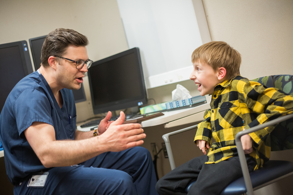 Gillette Children's patient Joshua Reis and Dr. Tenner Guillaume talk during a visit.