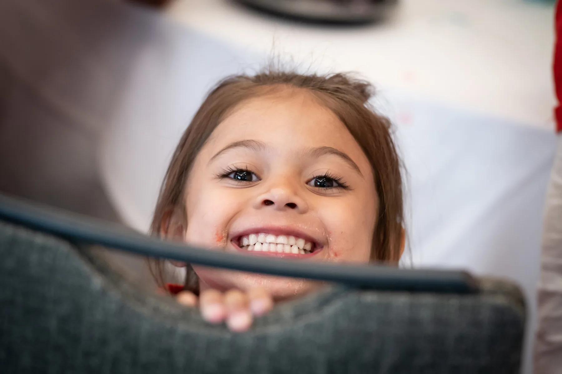 Happy child peaking over the edge of a chair - Gillette Children's.