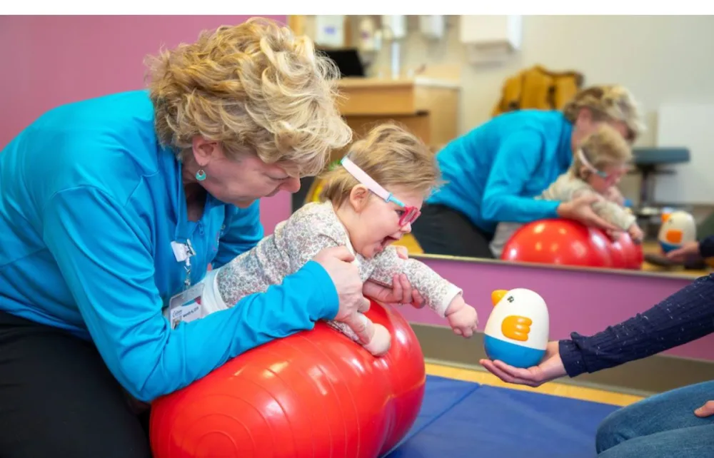 OT Wendy Aeling helps Elliana work on her hand strength and coordination by having her reach for a toy at Gillette Children's.