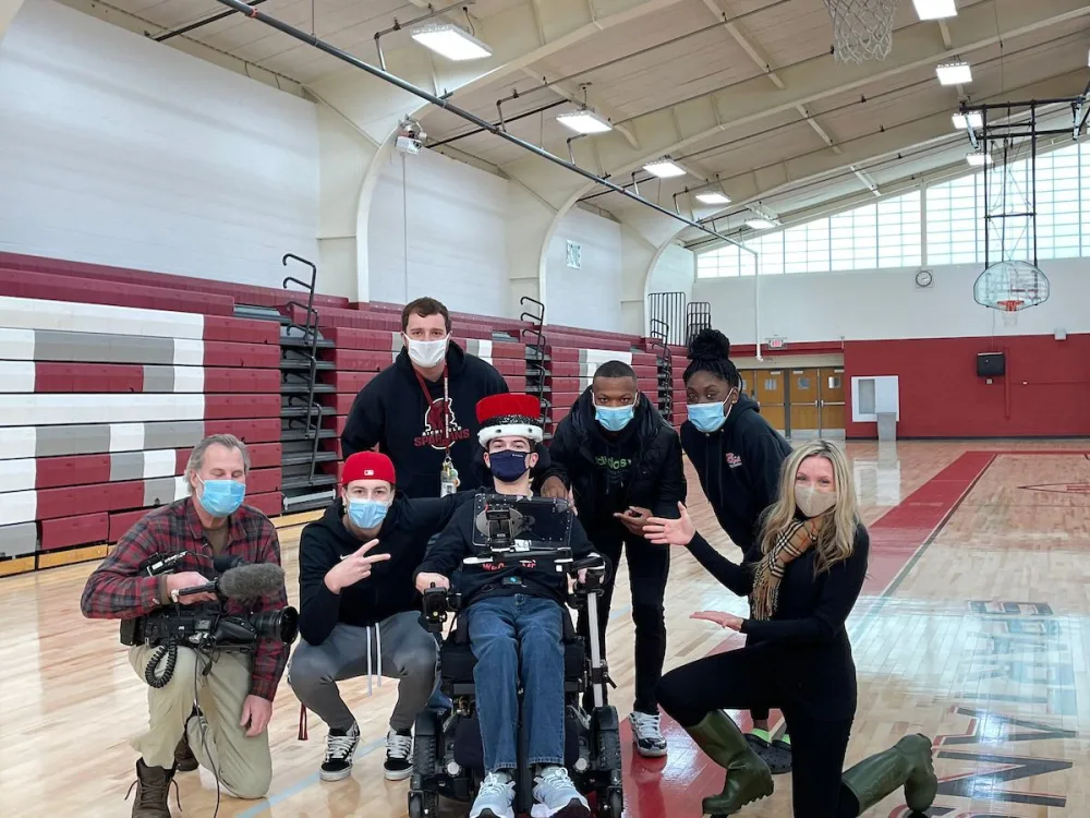 Joe Carr smiles with school faculty with Gillette Children's.
