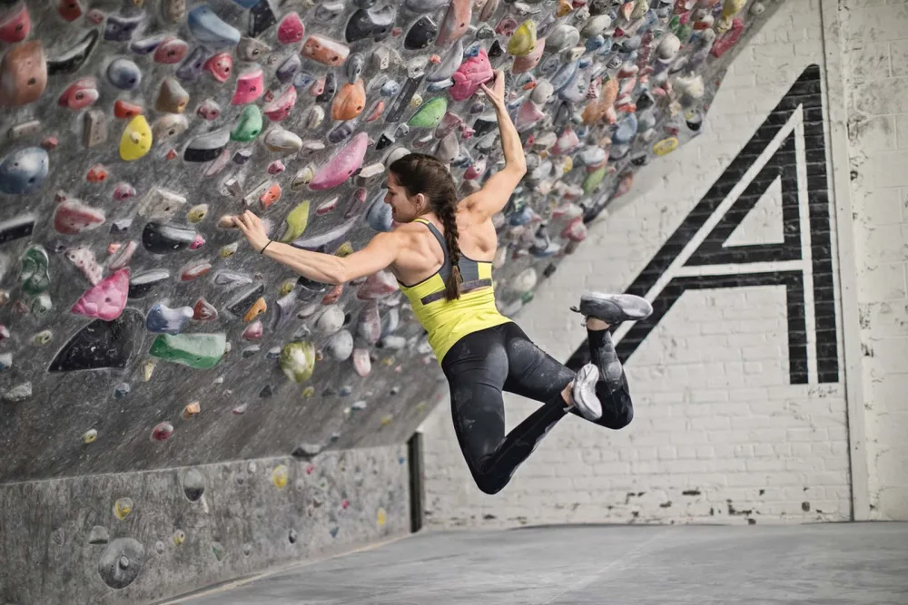 Photo of Kyra climbing on rock wall with Gillette Children's.