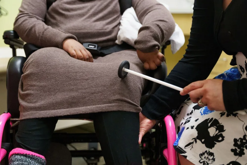 Provider taps on knee of patient at Gillette Children's.