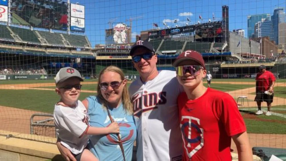 Owen and family pose in front of Minnesota Twins Baseball field with Gillette Children's.