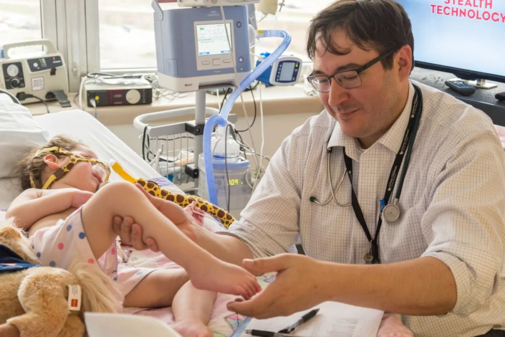 Randal Richardson, MD, examines the muscle tone of a SMA patient at Gillette Children's.