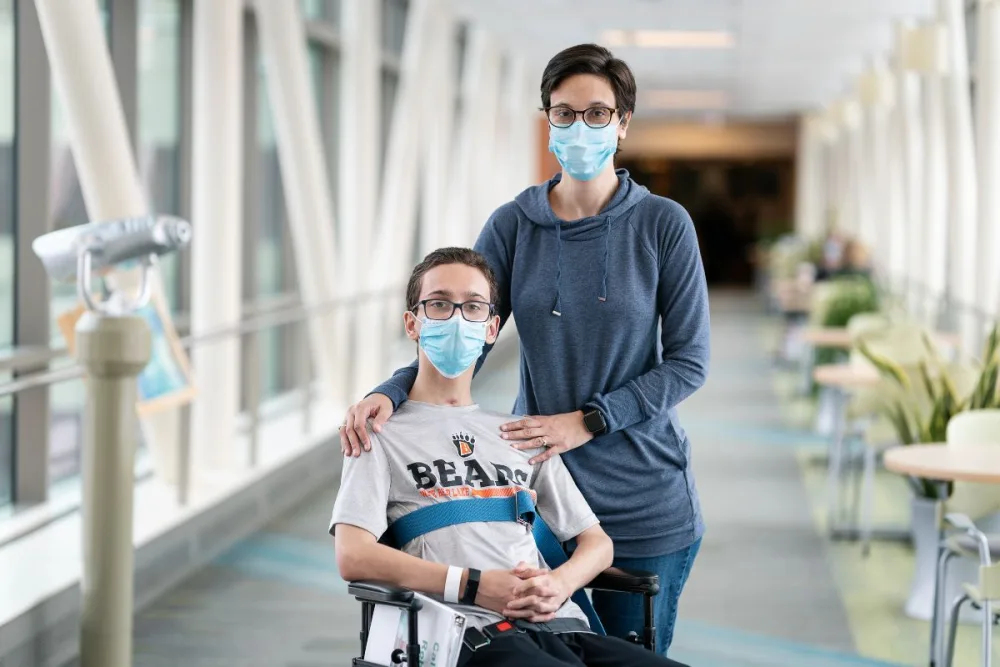 Caleb and his mom smile at Gillette Children's.