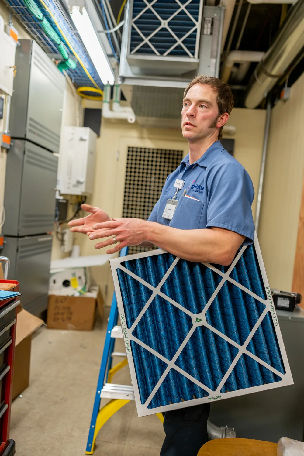 Gillette Facilities Engineer Shane Madaris stands holding an air filter in a mechanical room.