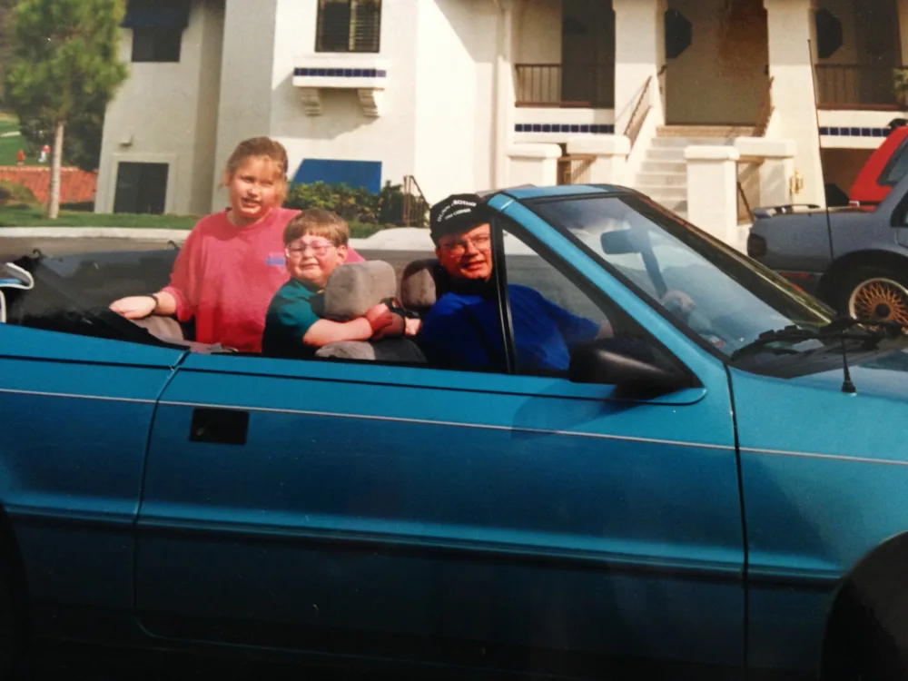 Robert riding as child in car with Gillette Children's.