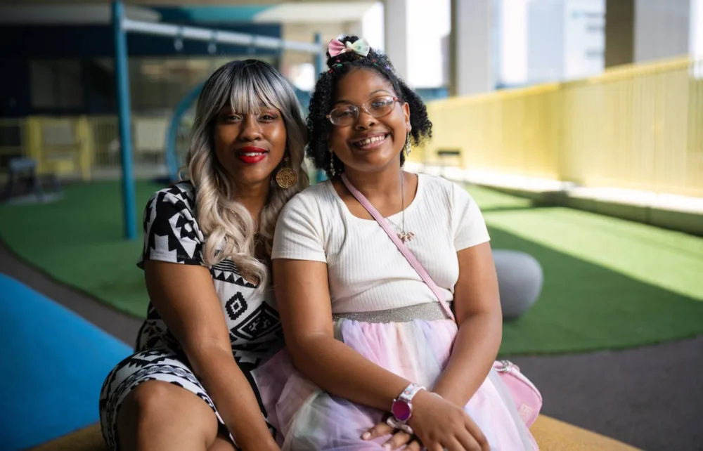 Patient ZaLayaa and her mother Jazzalette sit next to eachother and smile at Gillette Children's.