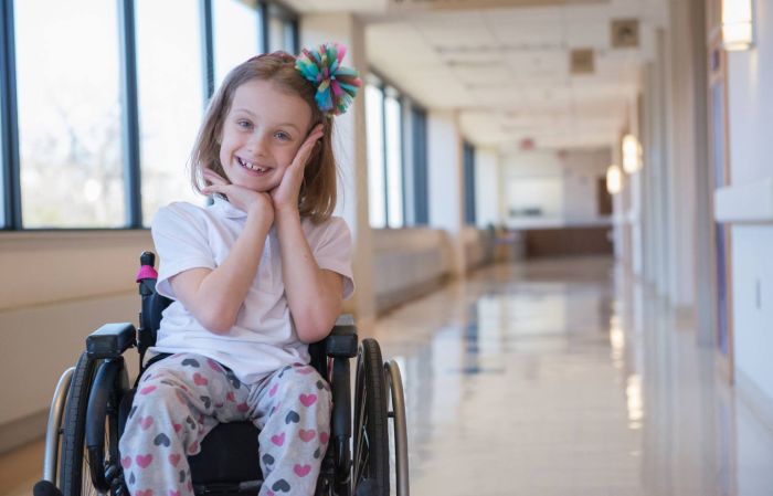 Gillette Children's patient Maddy Lavalier frames her face with her hands for a portrait in a hallway.
