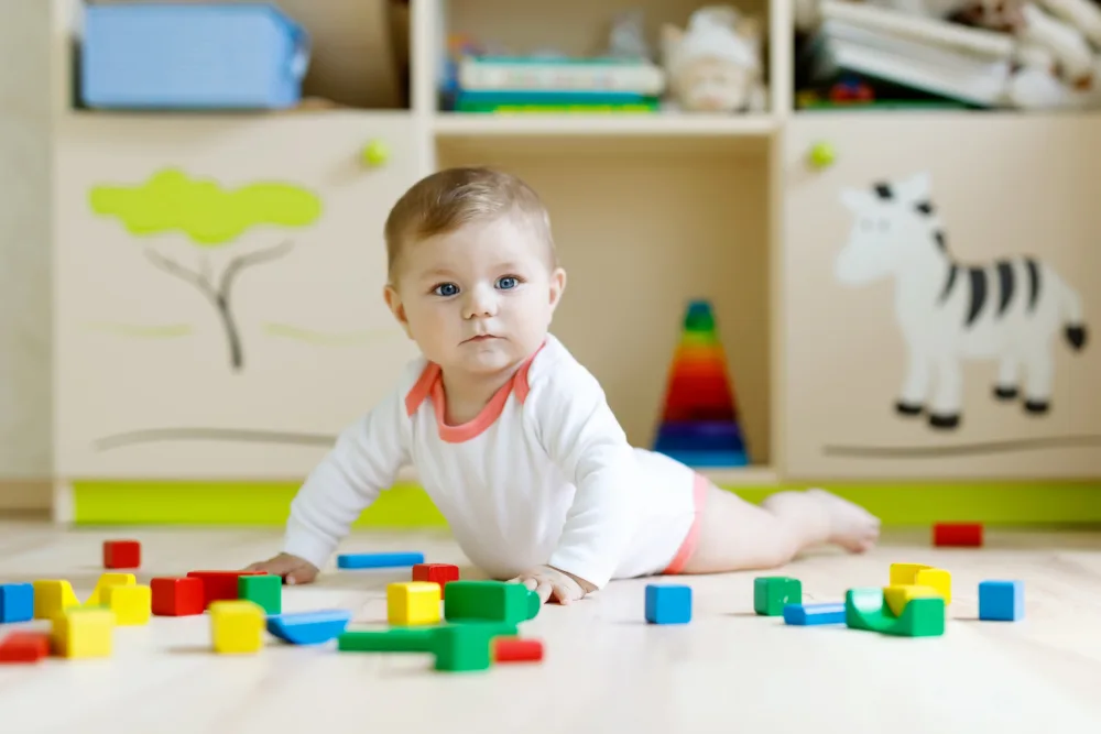 Baby on tummy with blocks strewn around.