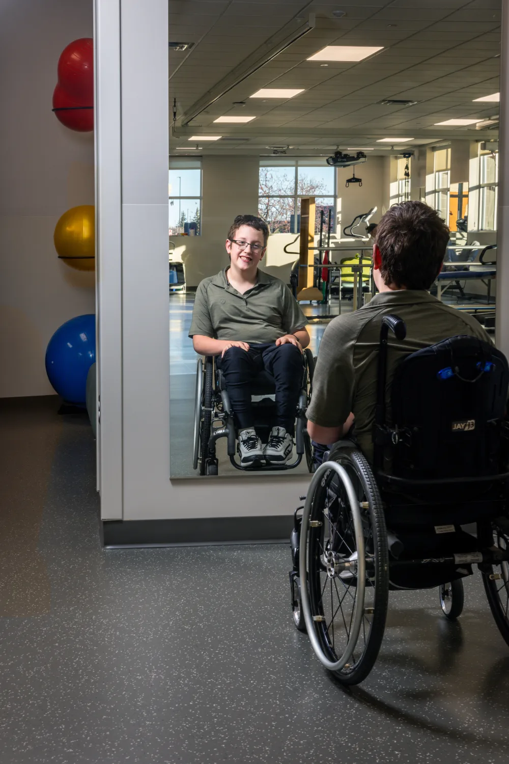 John Buettner poses in front of a mirror in a rehabilitation gym at Gillette Children's.