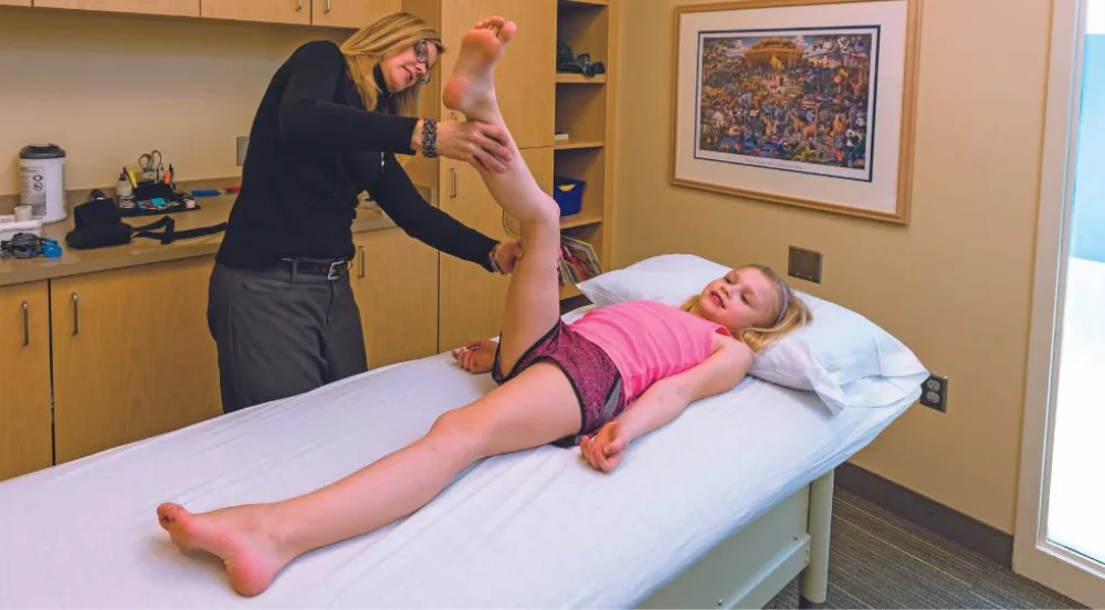 Child on exam bed with provider in gait lab  - Gillette Children's.