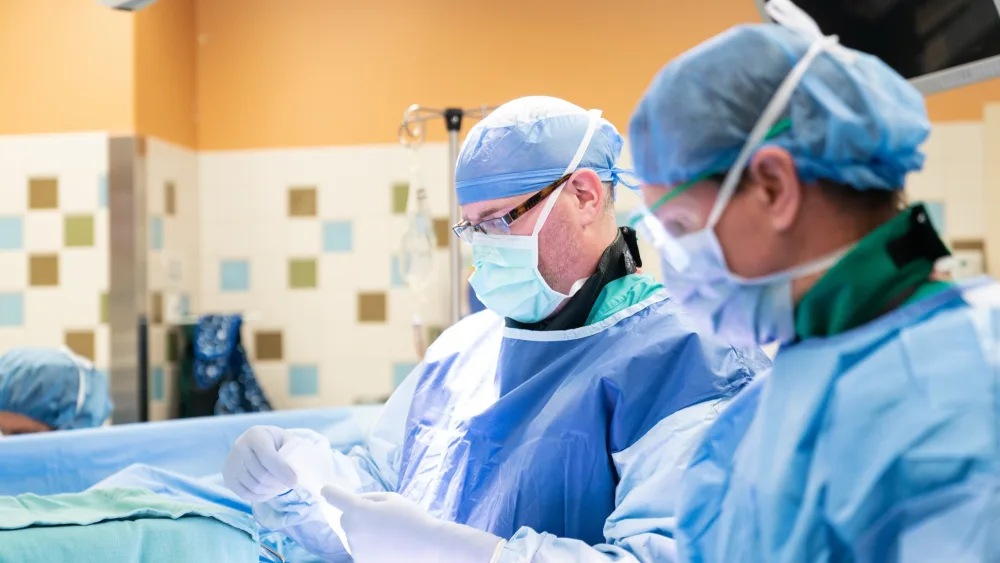 Two surgeons in scrubs with face masks are shown during surgery on a young patient at Gillette Children's.