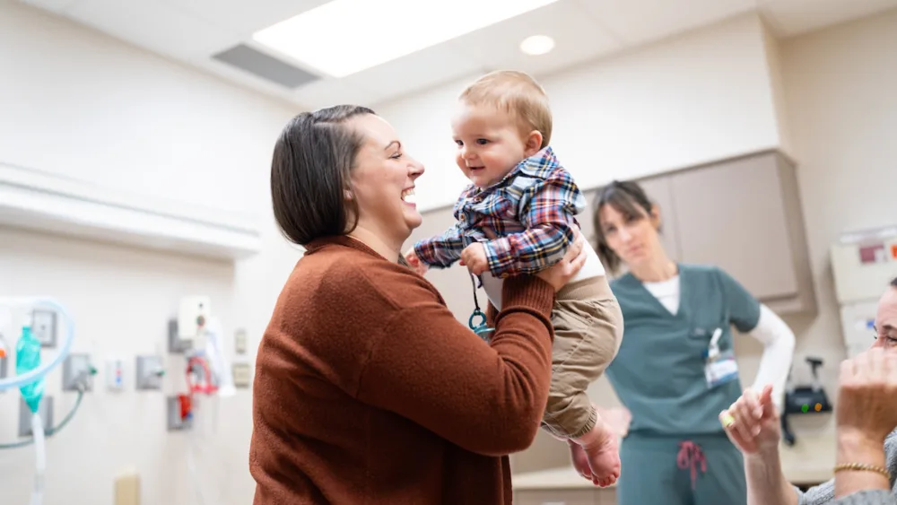 Wyatt Krentz is held by his smiling mother Kaitlin in the Clubfoot Clinic
