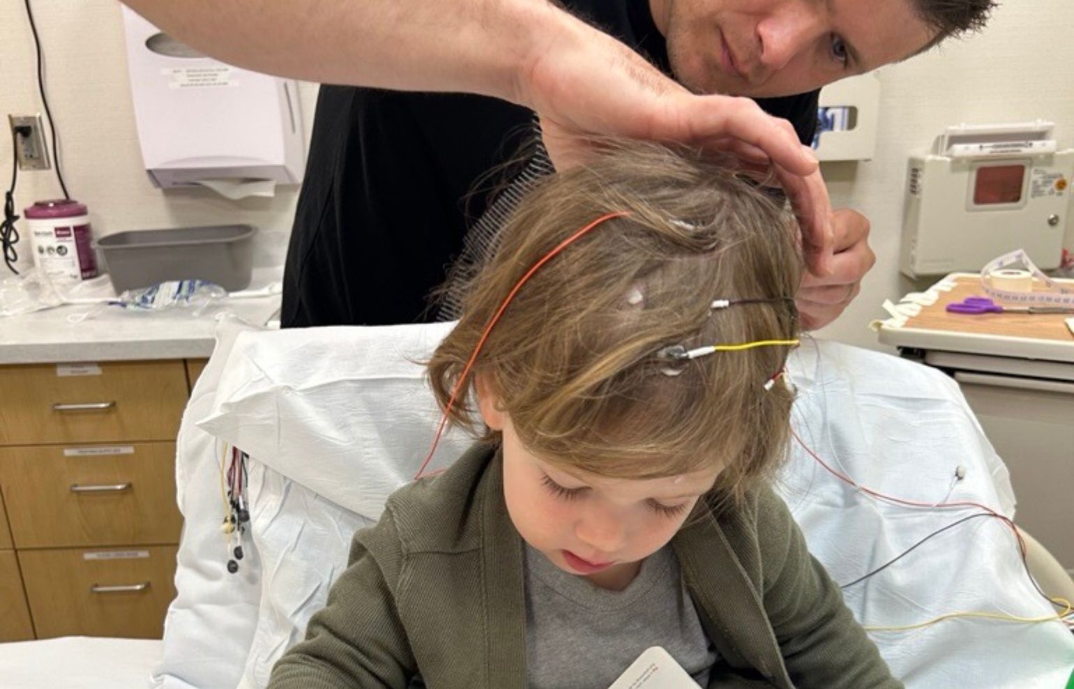 A toddler has electrodes placed on his scalp by a neurodiagnostic technician at the Gillette Children's Seizure Evaluation Clinic.