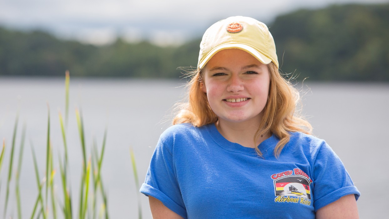 Gillette Patient Parris Oswald stands in front of a lake smiling.