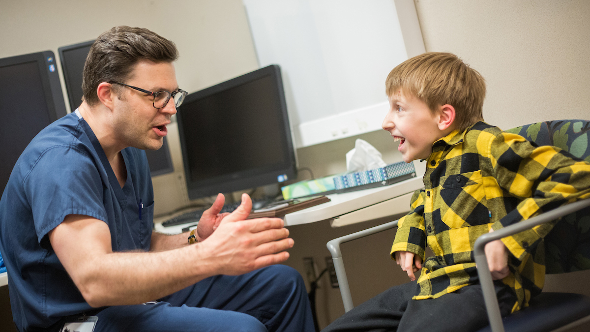 Gillette Children's patient Joshua Reis and Dr. Tenner Guillaume talk during a visit.