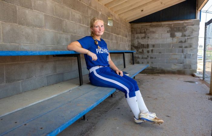 An adolescent girl poses in a baseball dugout on behalf of Gillette Children's.