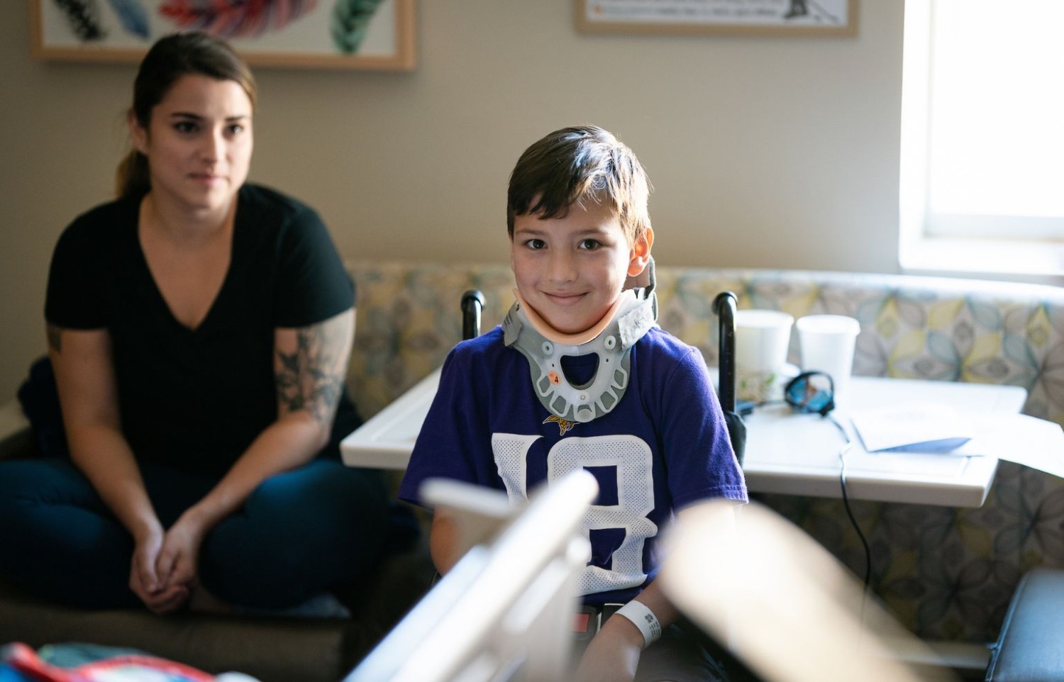 A patient wearing a neck brace smiles for a portrait on Gillette Children's inpatient unit.