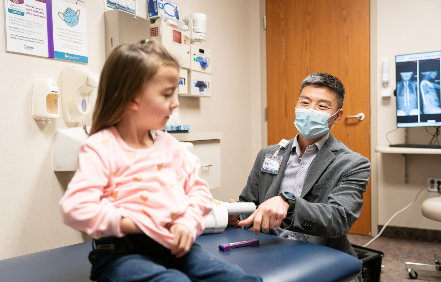 A young female patient chats with a doctor seated beside her at Gillette Children's.