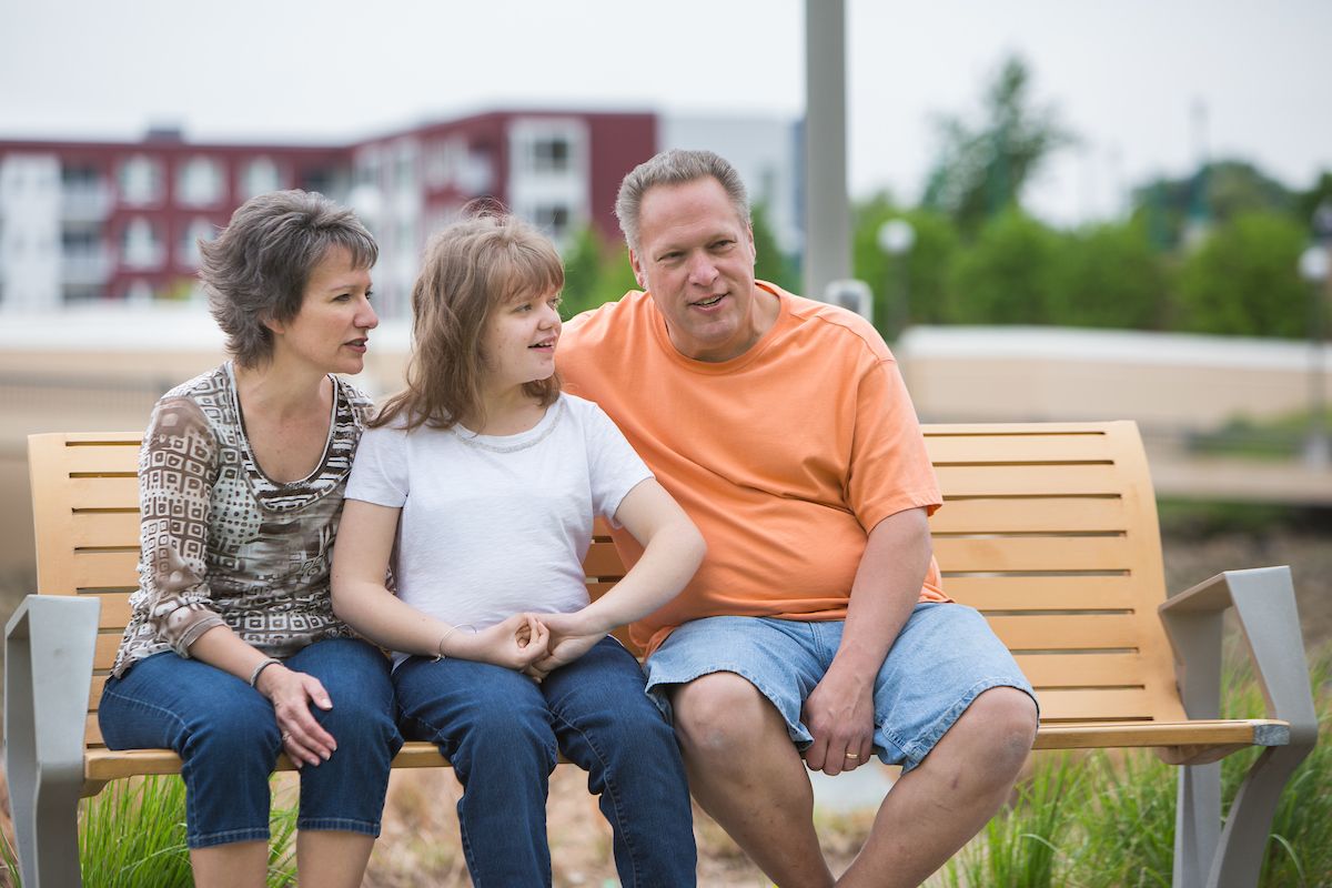 The Evert family sits on a park bench in St. Paul on a sunny day.