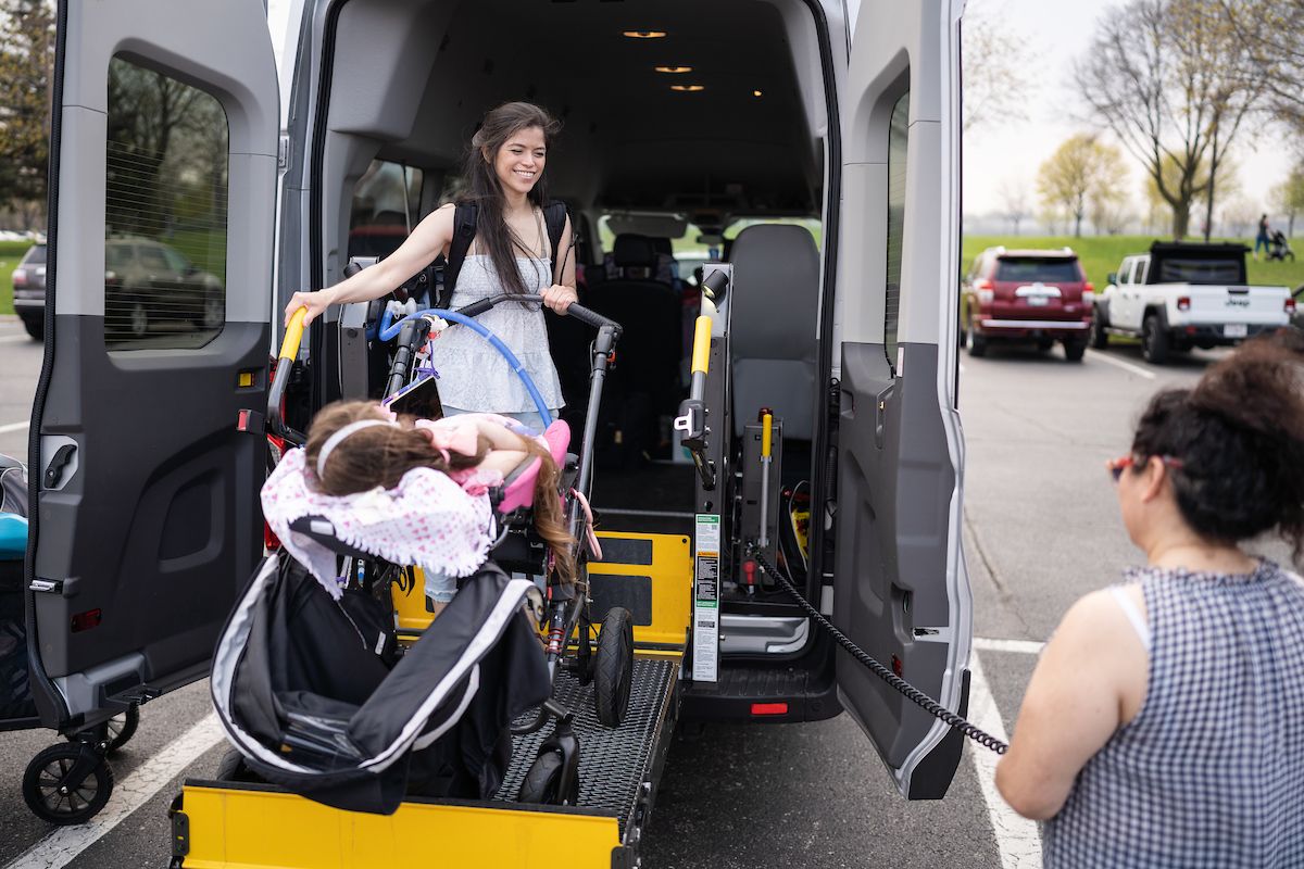 Anna helpes her daughter, Annika, on a special accessible van for safe transportation.