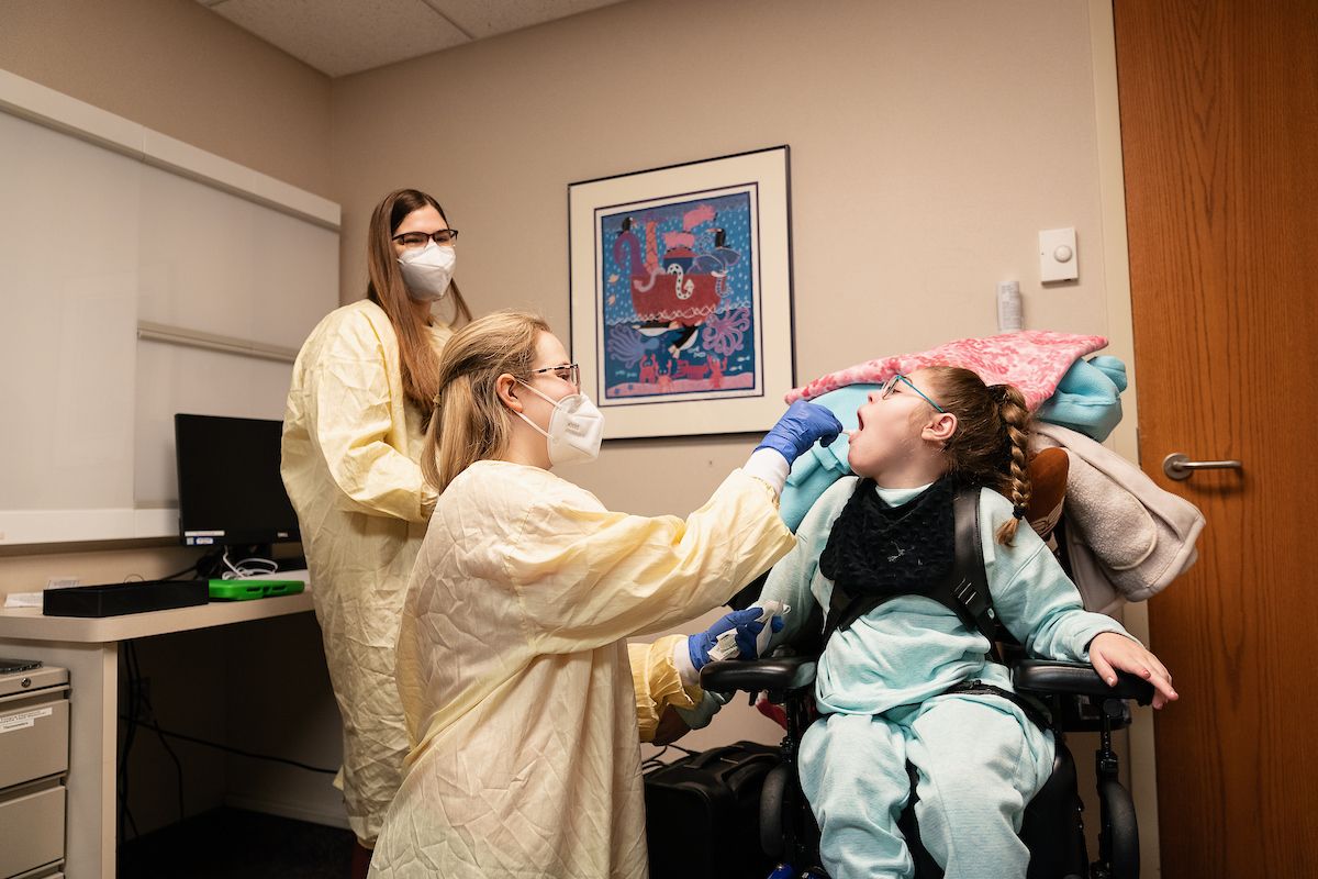 Two Gillette researchers take a sample from a patient who has cerebral palsy.