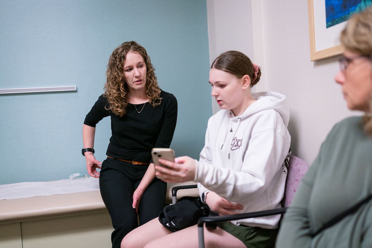 Natalie Stork, MD talks to a sports medicine patient in a clinic room.