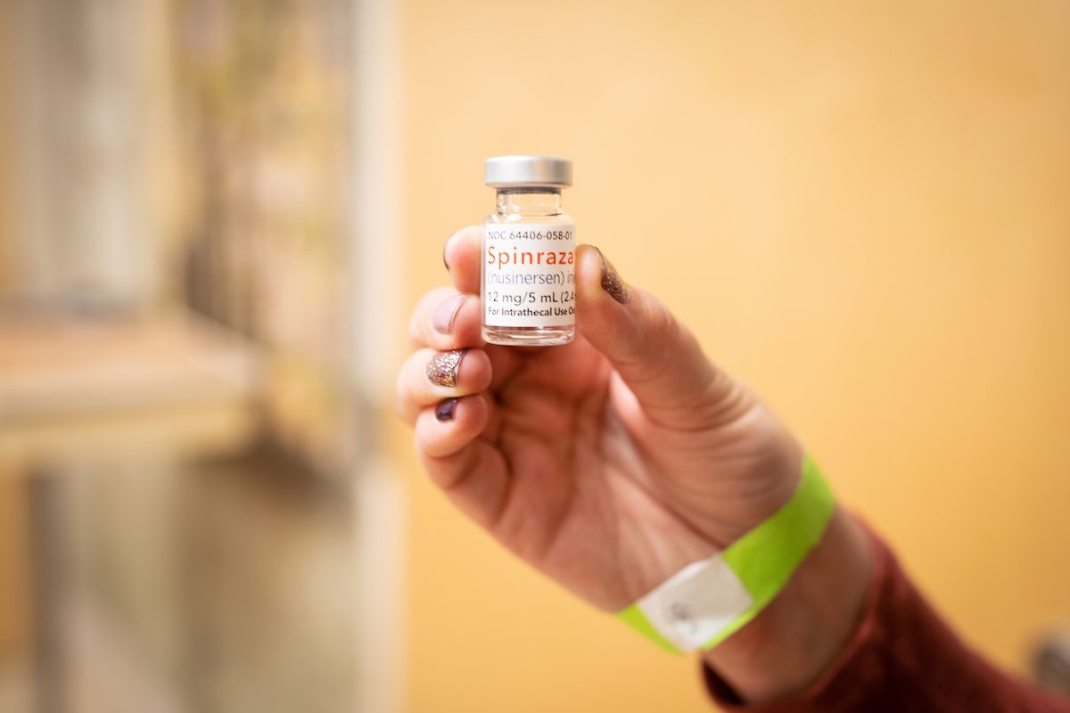 A hand holds a bottle of the SMA treatment, Spinraza.