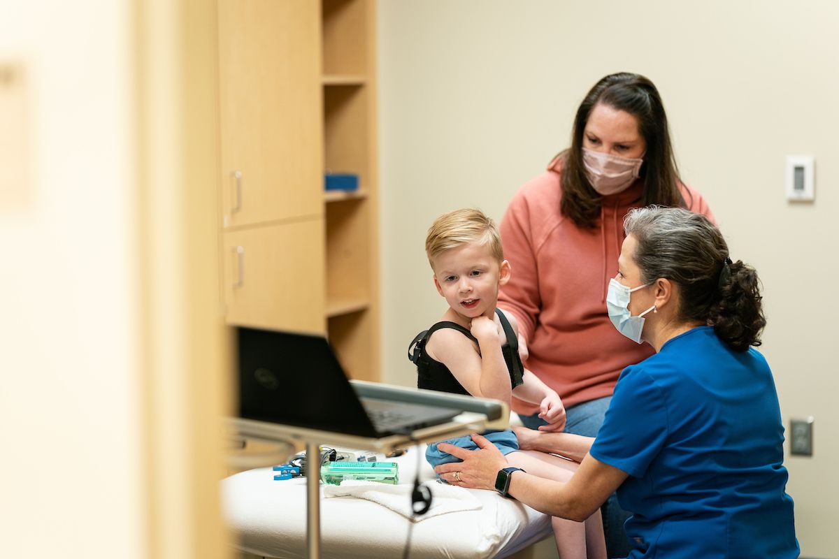 boy sitting on a table for gait analysis with a parent and a provider